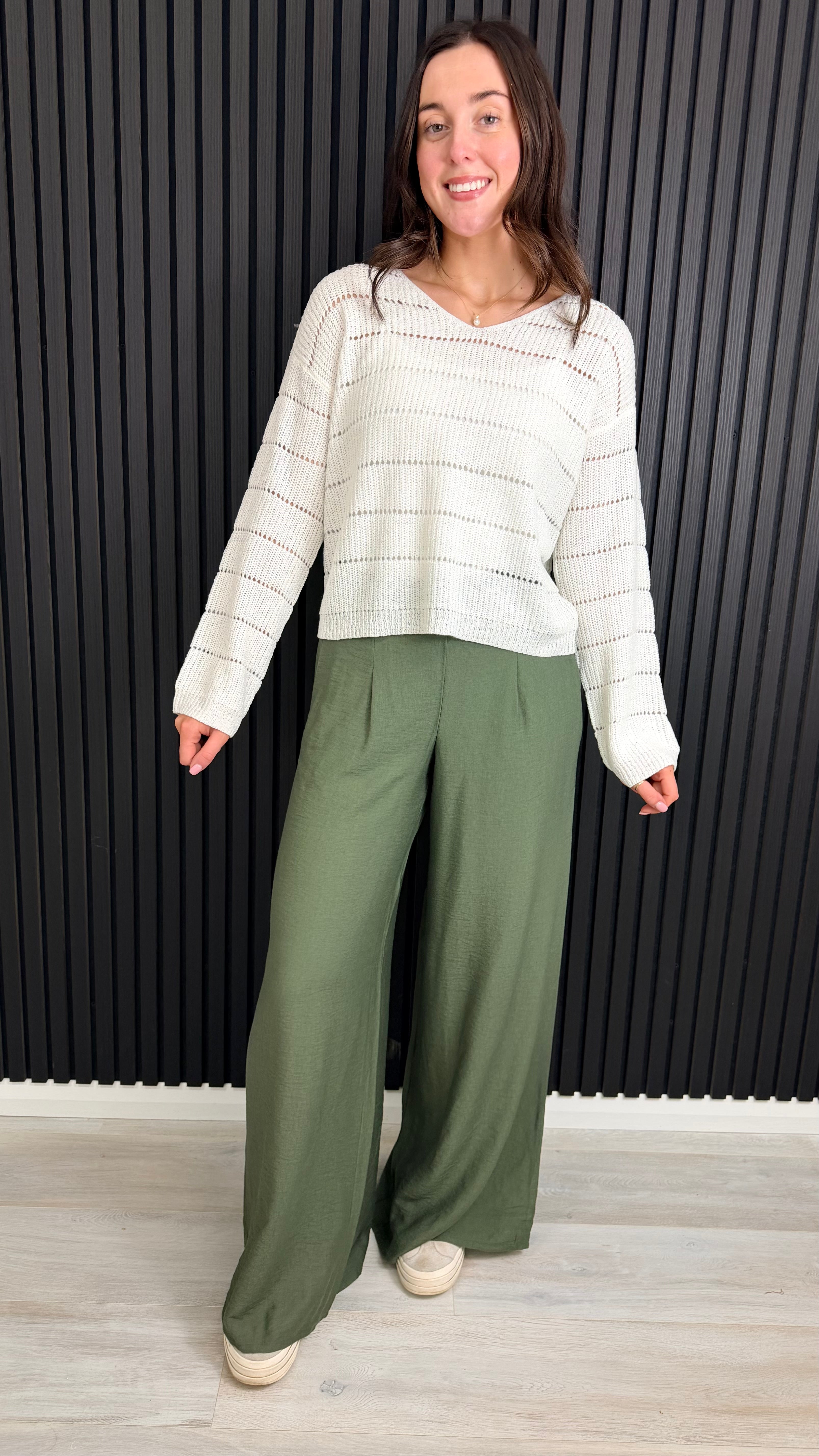Green wide-leg trousers styled casually with trainers