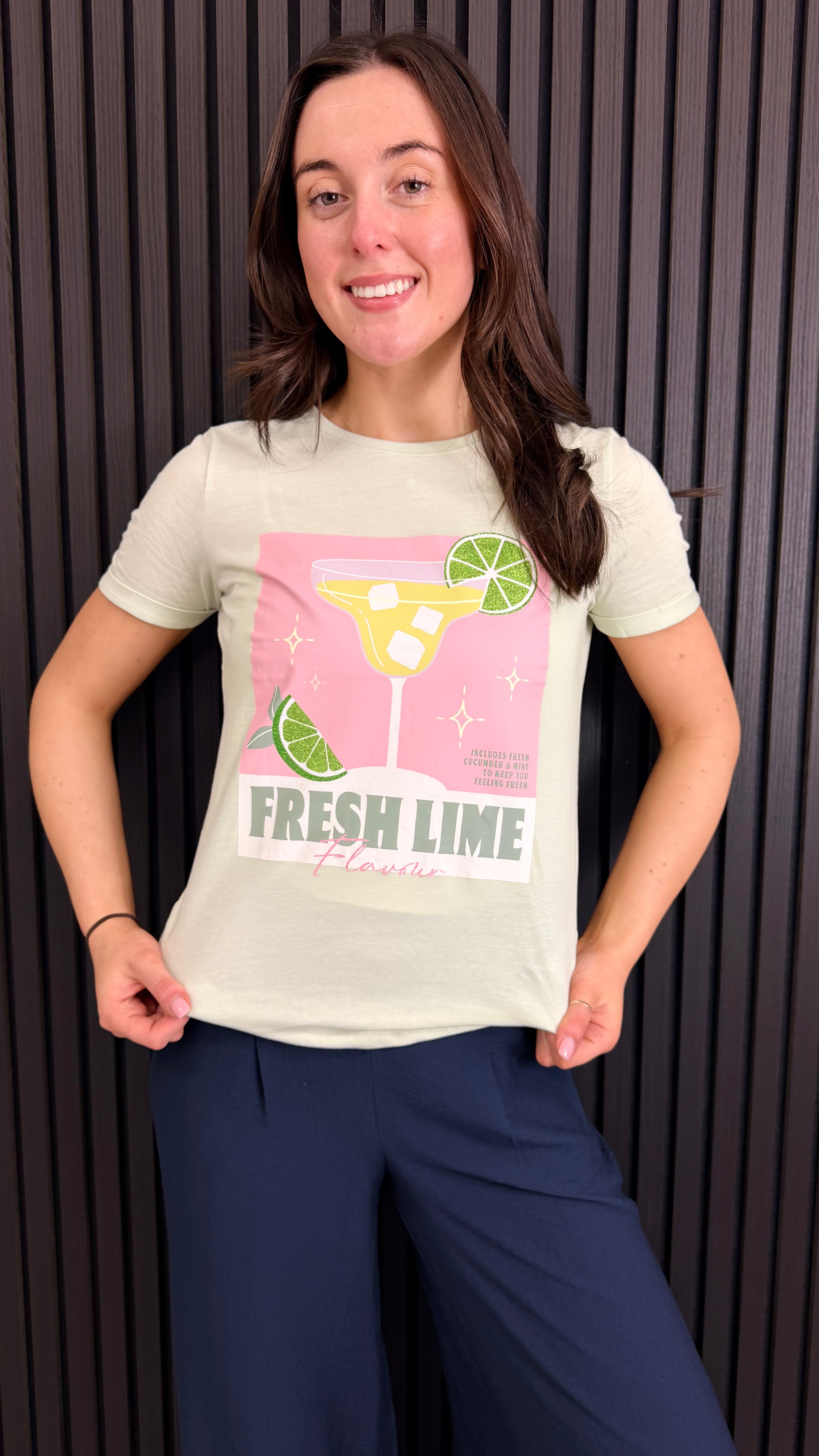 Front view of Fresh Lime graphic t-shirt styled with navy trousers.