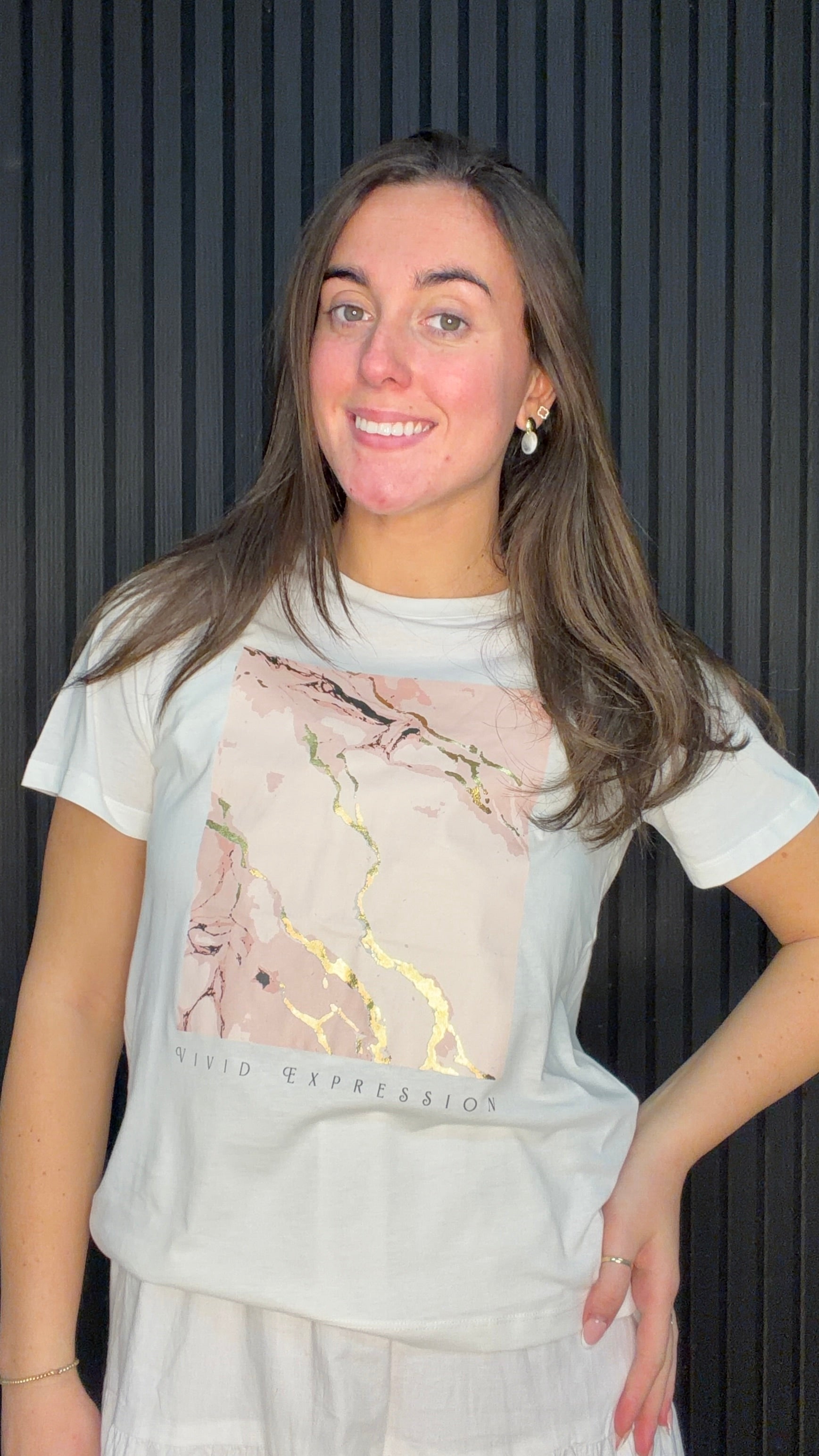 Model wearing the Lima Graphic T-Shirt in Cloud Dancer featuring a marble-inspired print with metallic gold detailing.