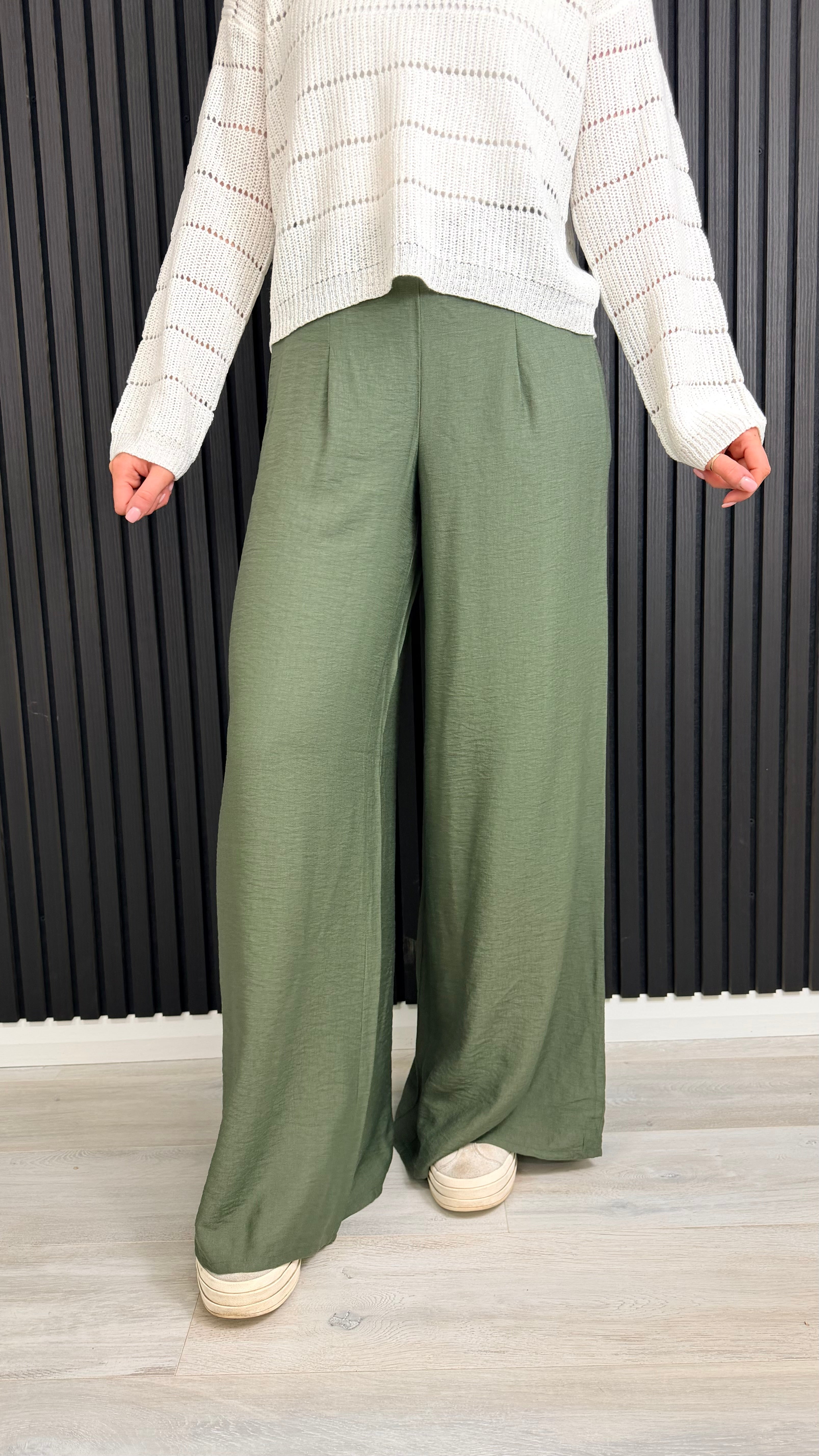 Green wide-leg trousers styled casually with trainers