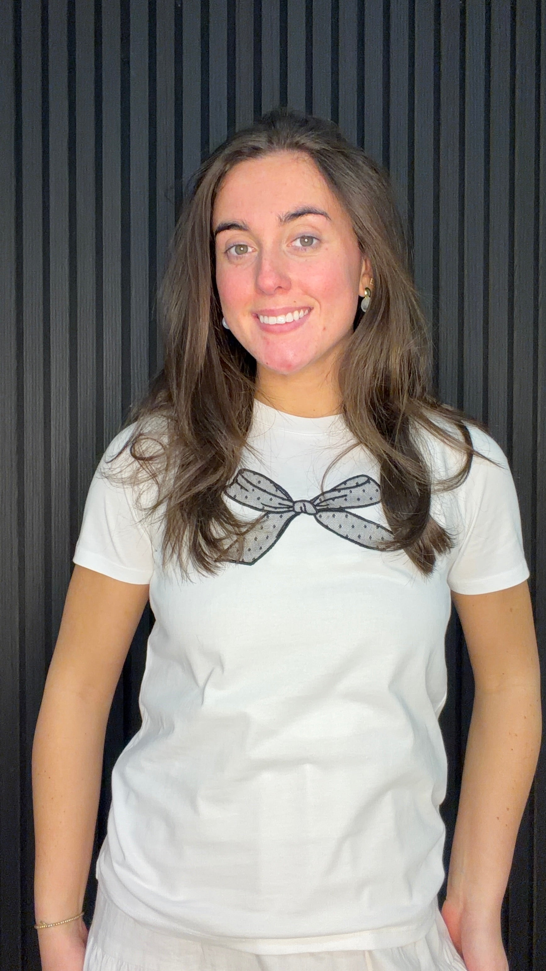 Model wearing the Marie Bow T-Shirt in White with a black mesh bow detail on the neckline.